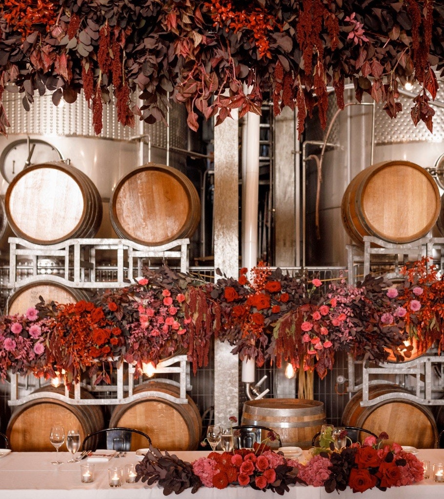 Rack of wine barrels with wedding floral installation.